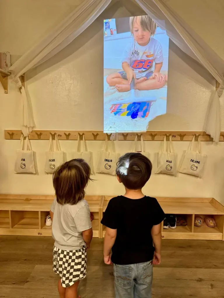 Children watching a class presentation together at Here & There Preschool