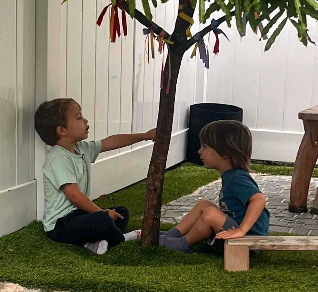 Two children engaged in a small group outdoor learning activity at Here & There Preschool