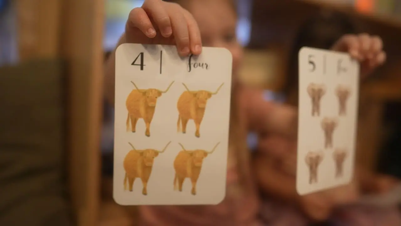 hildren learning early math concepts with hands-on educational cards at Here & There Preschool