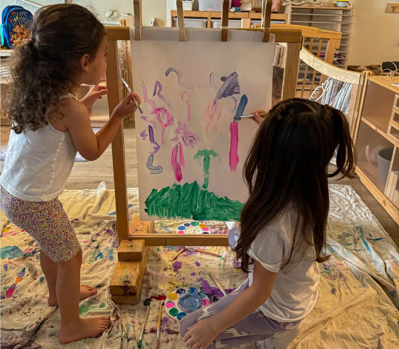 Children expressing creativity through collaborative painting at Here & There Preschool